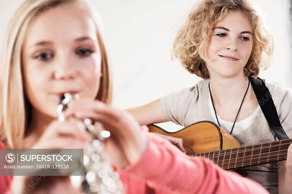 Two teenage girls playing guitar and oboe