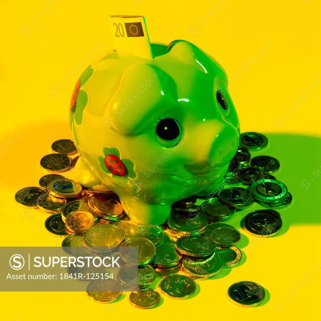 Piggy bank with twenty Euro note and scattered coins