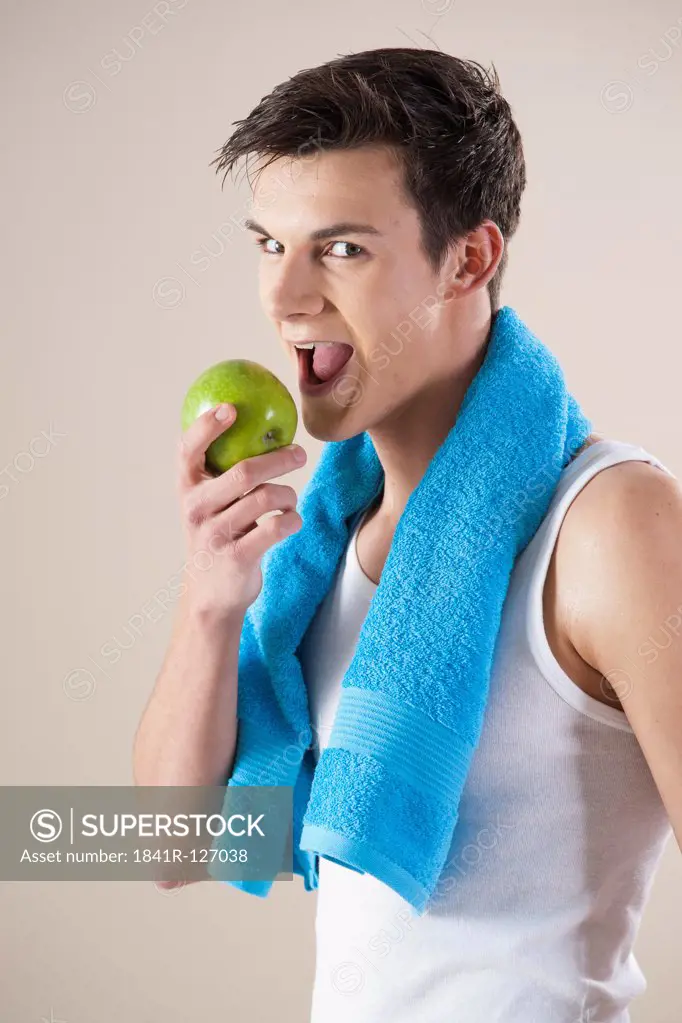 young smiling man bites in an apple