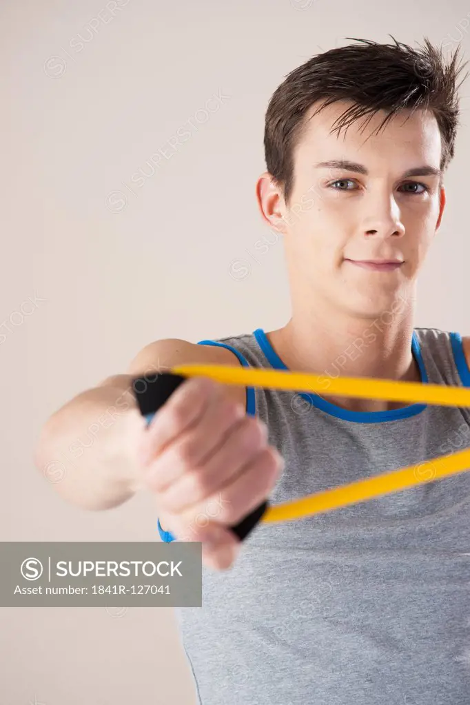 young man doing exercises with fitness strap