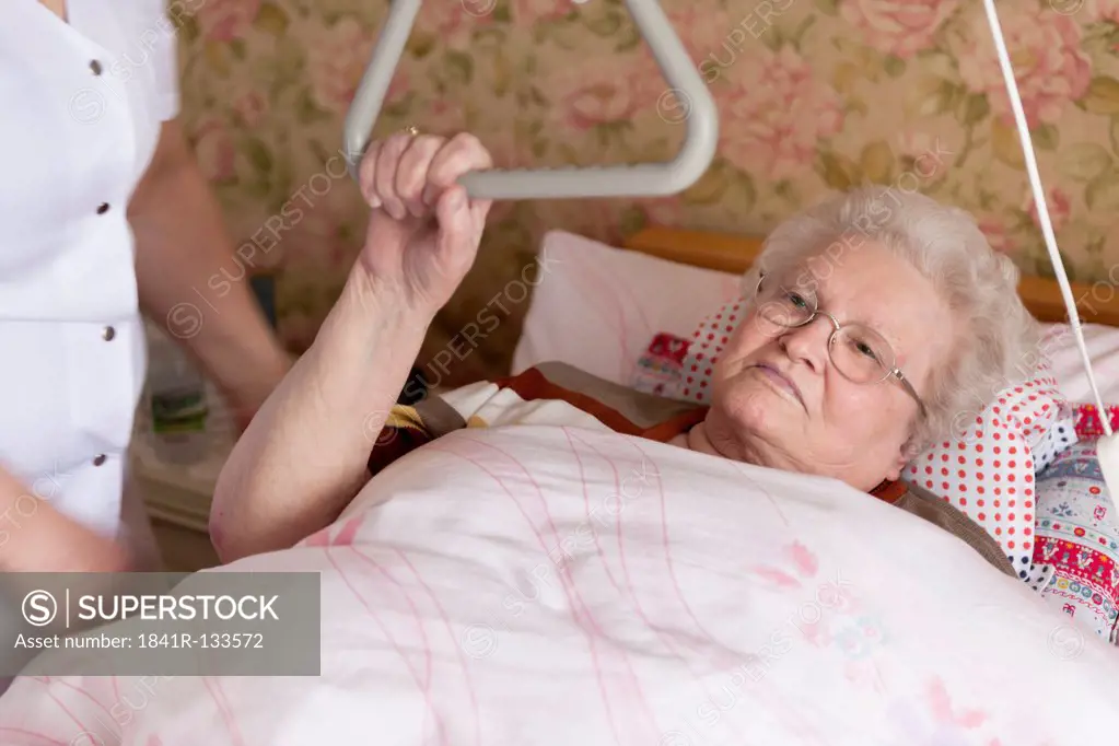 Geriatric nurse and old woman lying in sickbed