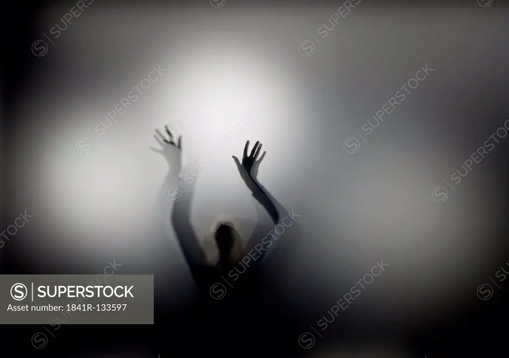 Silhouette of a person with raised hands
