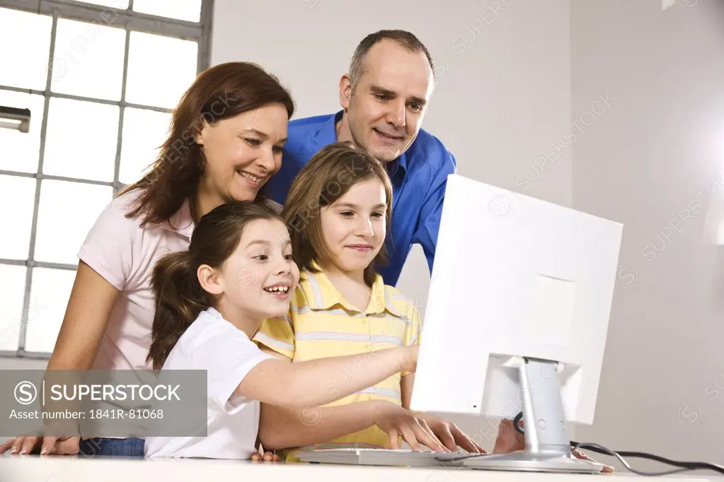 Family smiling while watching on computer screen