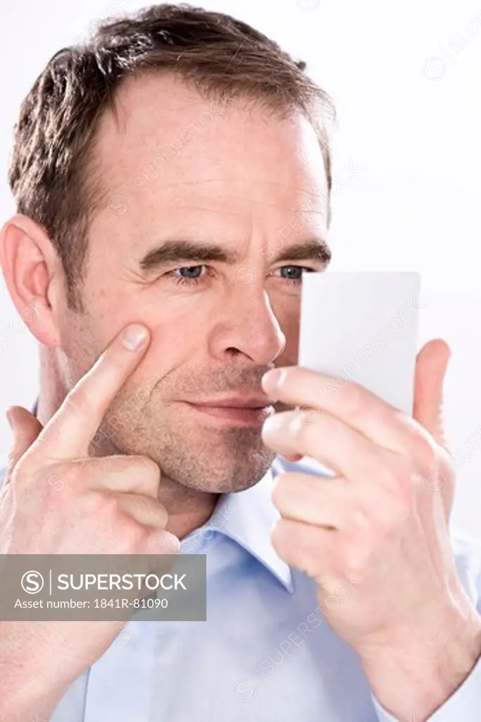 Man holding hand mirror and examining his face