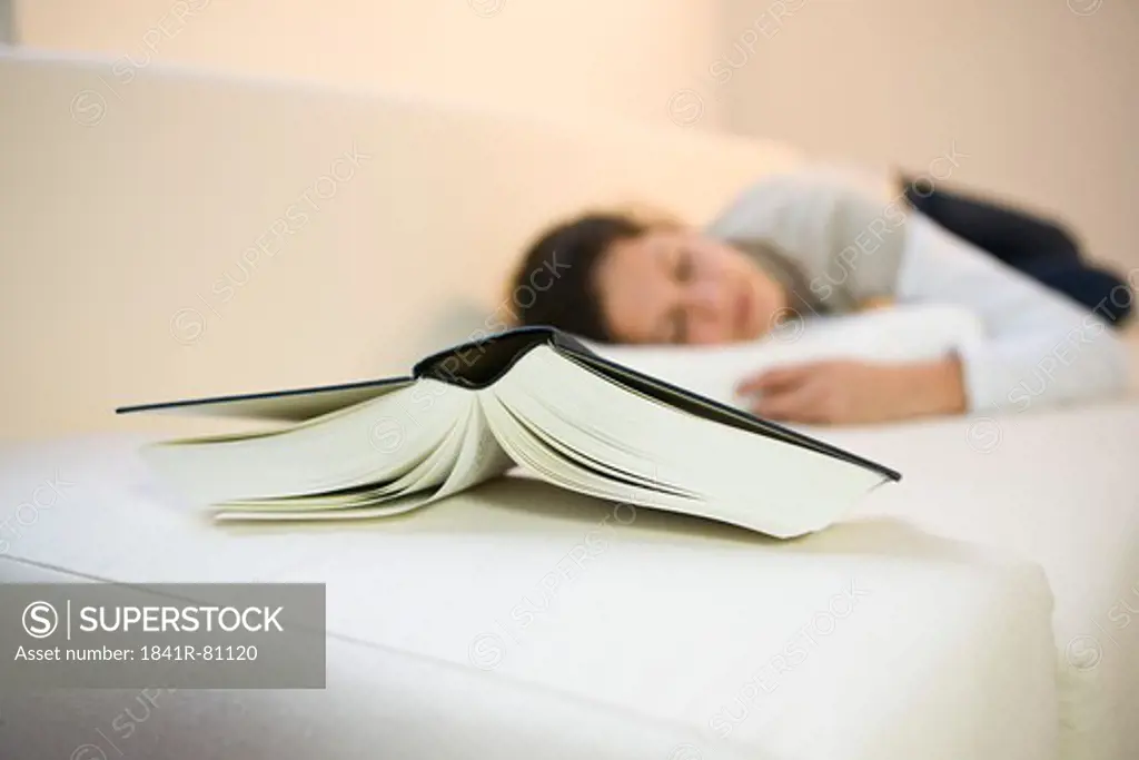 Close-up of book with girl lying on couch