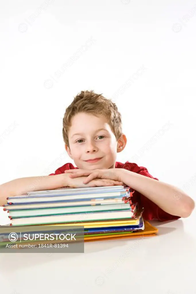 Boy leaning on books and smiling