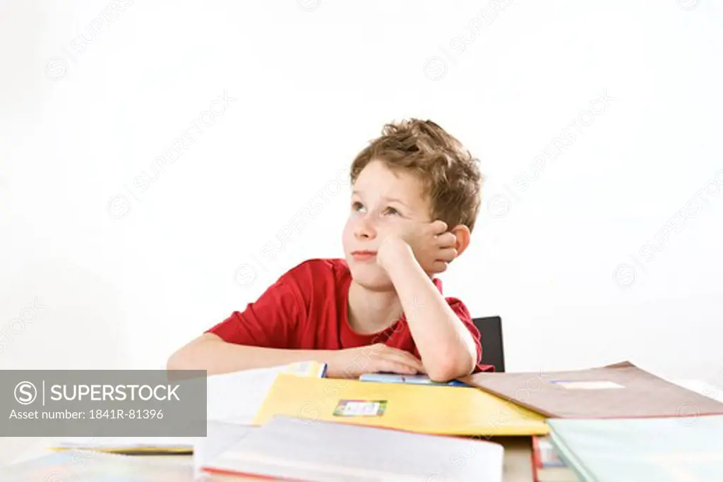 Boy leaning on books and thinking