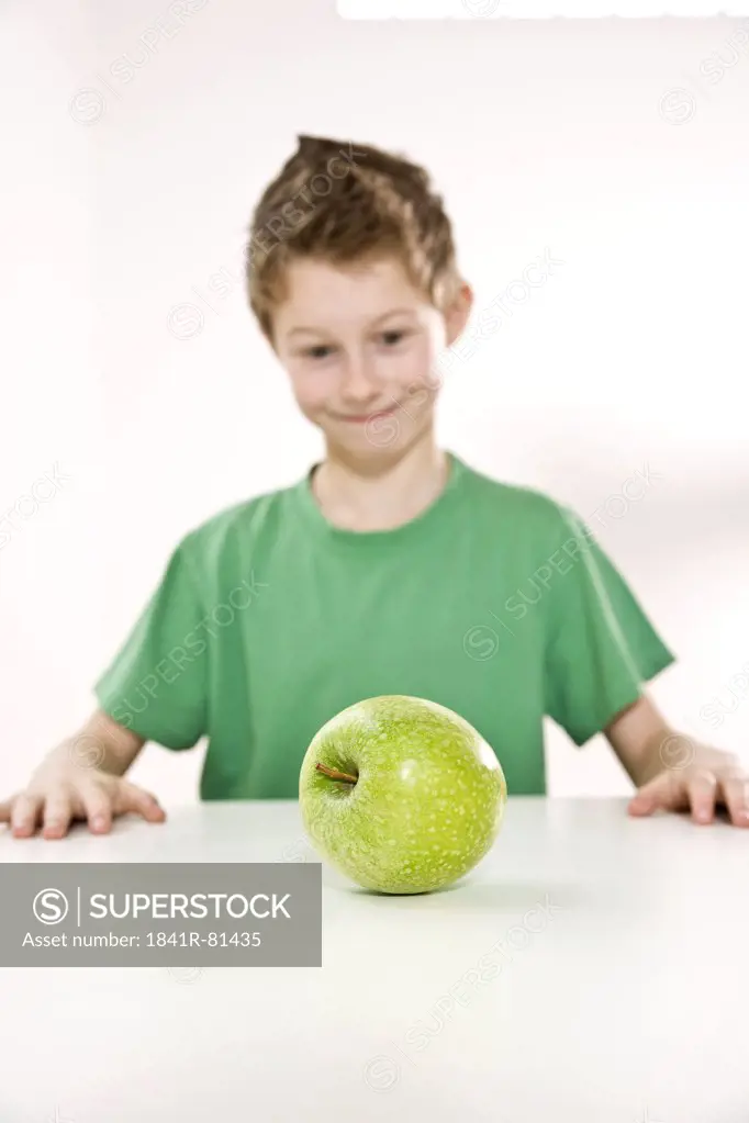Boy looking at granny smith apple