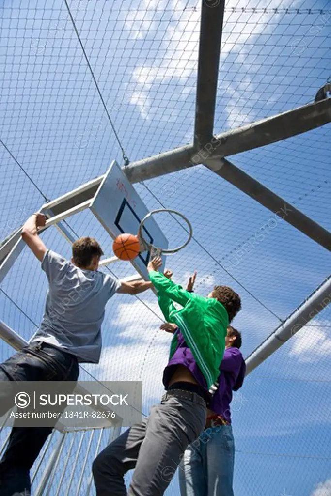 Boys playing basketball, low angle view