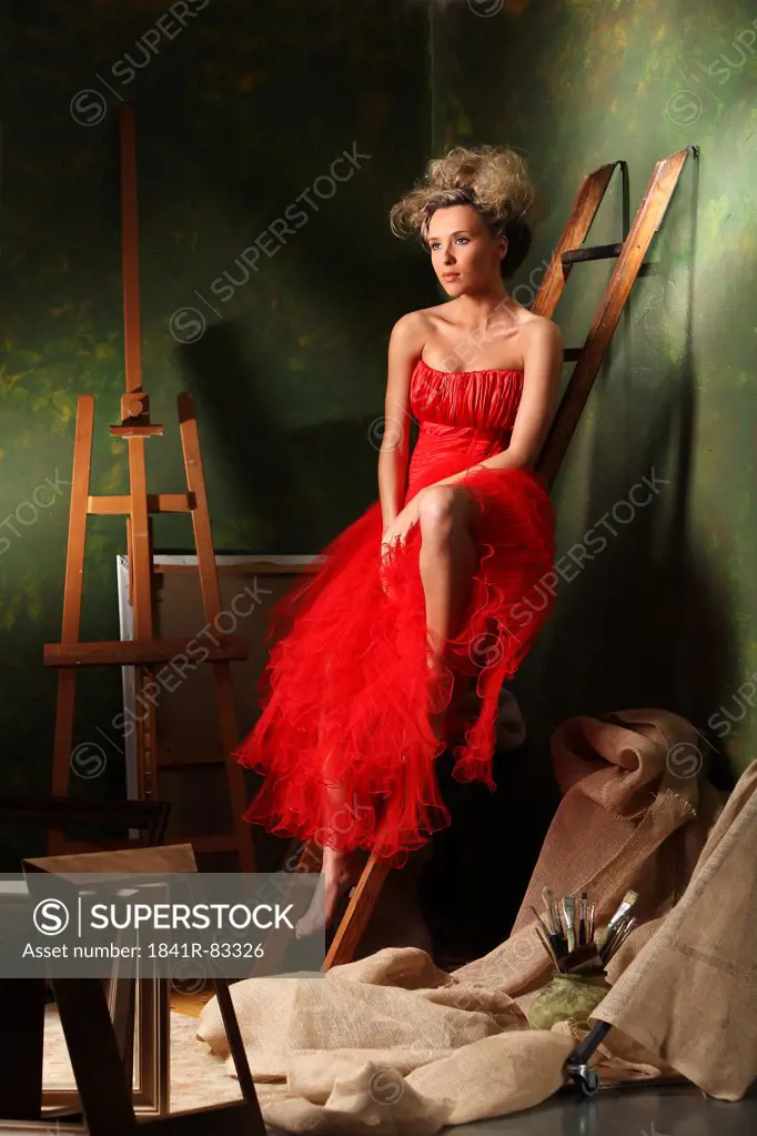 Woman in a red dress sitting on a ladder