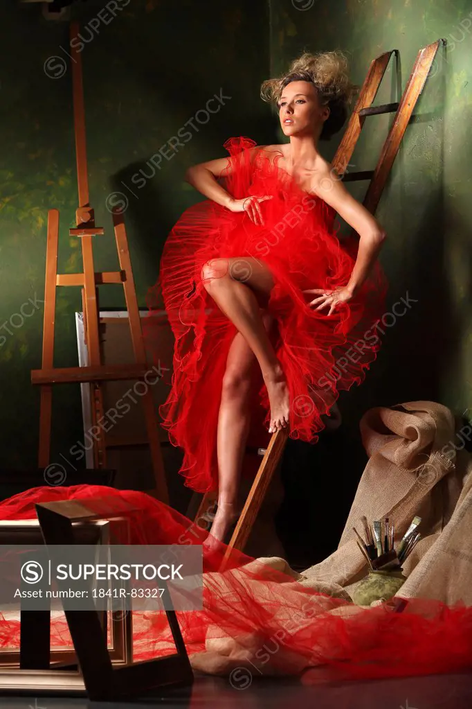 Woman posing in a red dress on a ladder