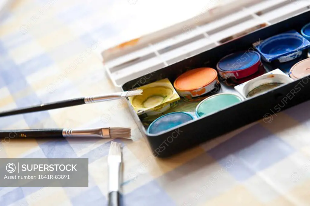 Watercolours and paint brushes on a table, close-up