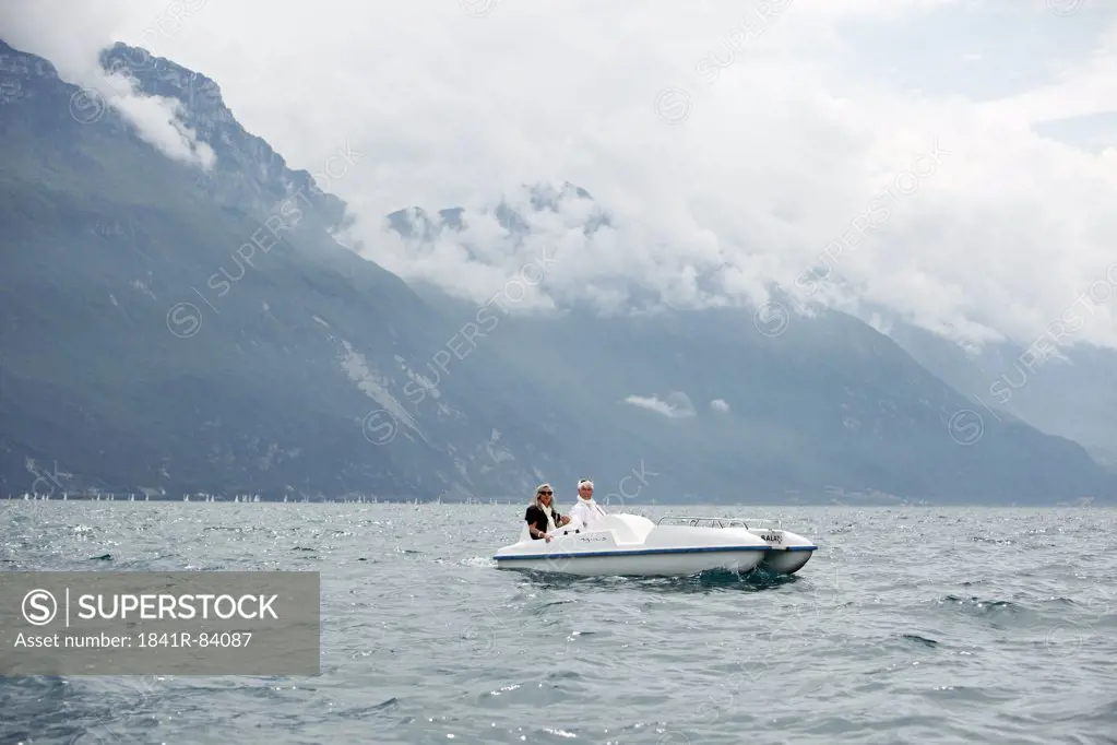 Senior couple with pedal boat in mountain scenery, Italy