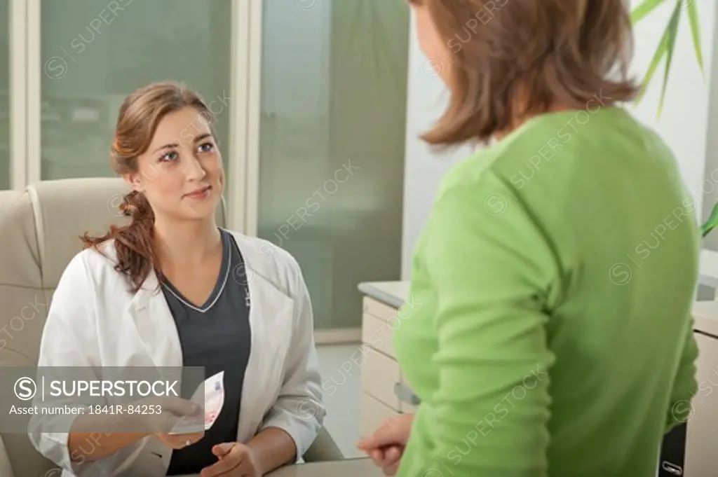 Female patient and doctor's assistant at desk with ten Euro