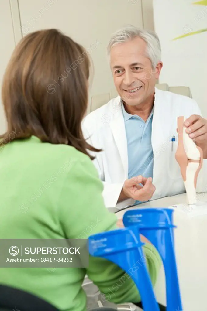 Doctor showing female patient artificial knee joint