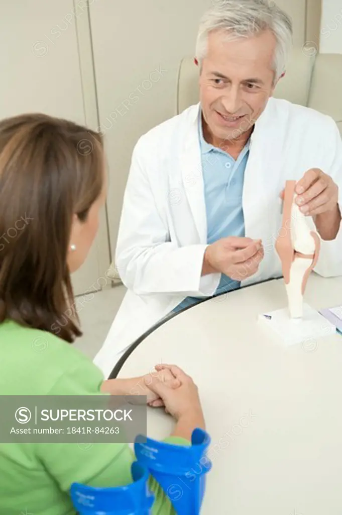 Doctor showing female patient artificial knee joint