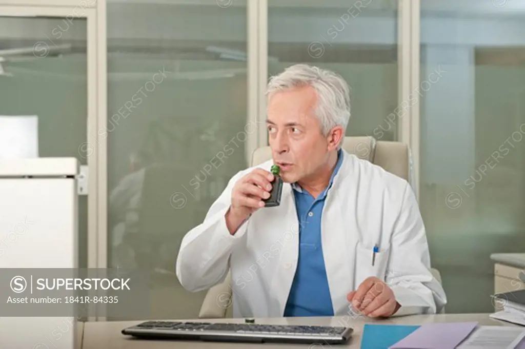Doctor at desk drinking liquor secretly