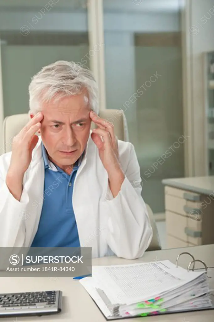 Doctor at desk rubbing his sleeves
