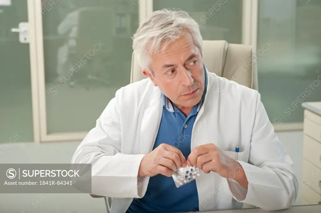 Doctor at desk taking tablet secretly