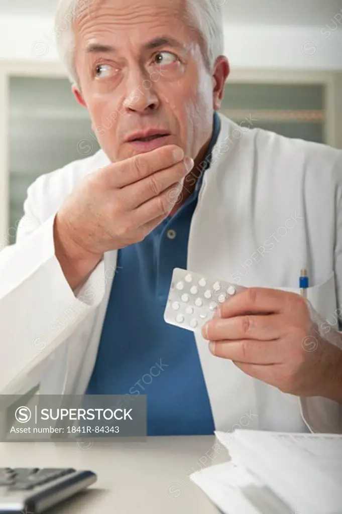 Doctor at desk taking tablet secretly