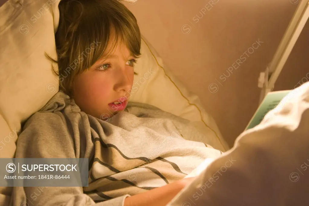 Close-up of boy reading book on bed