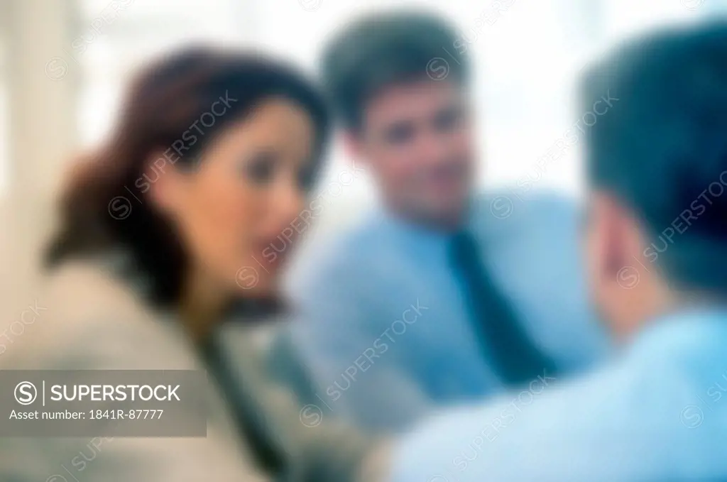 Defocused view of three businesspeople discussing in meeting