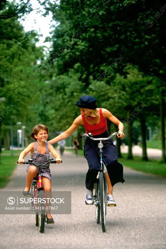 Woman and girl cycling on road