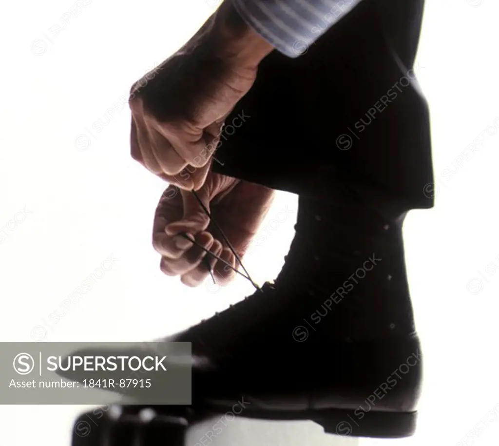 Low section view of man tying his shoelace