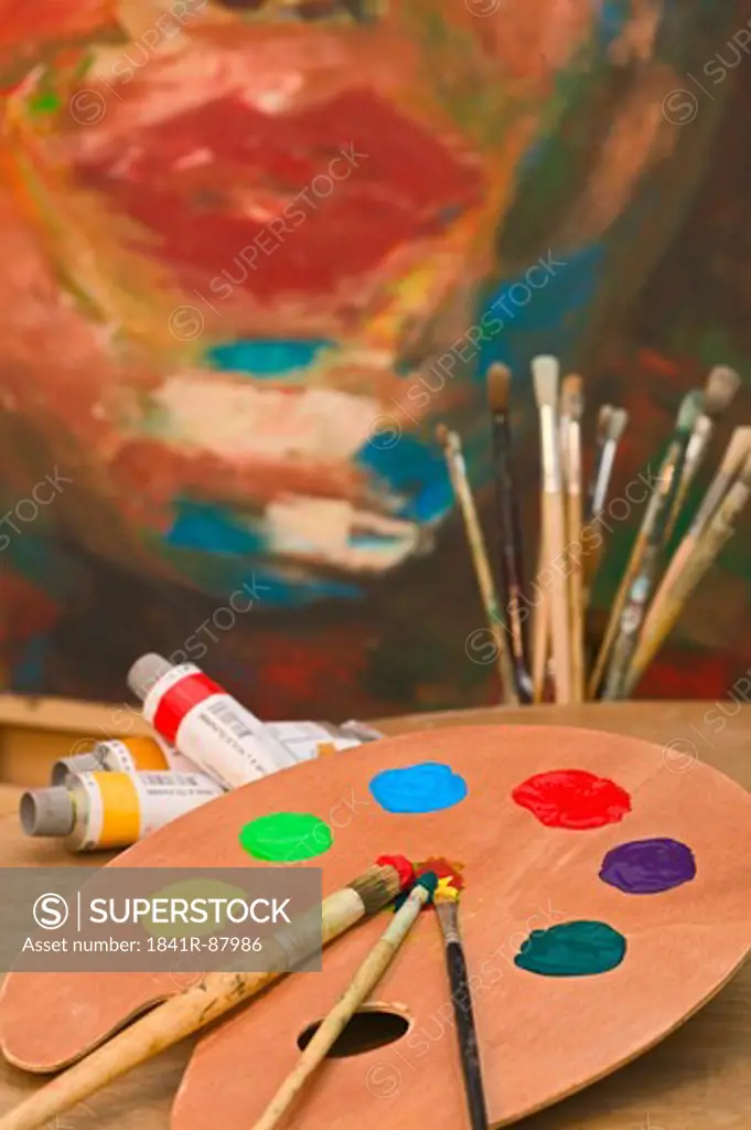Close-up of paint tray with paintbrushes and tubes on table