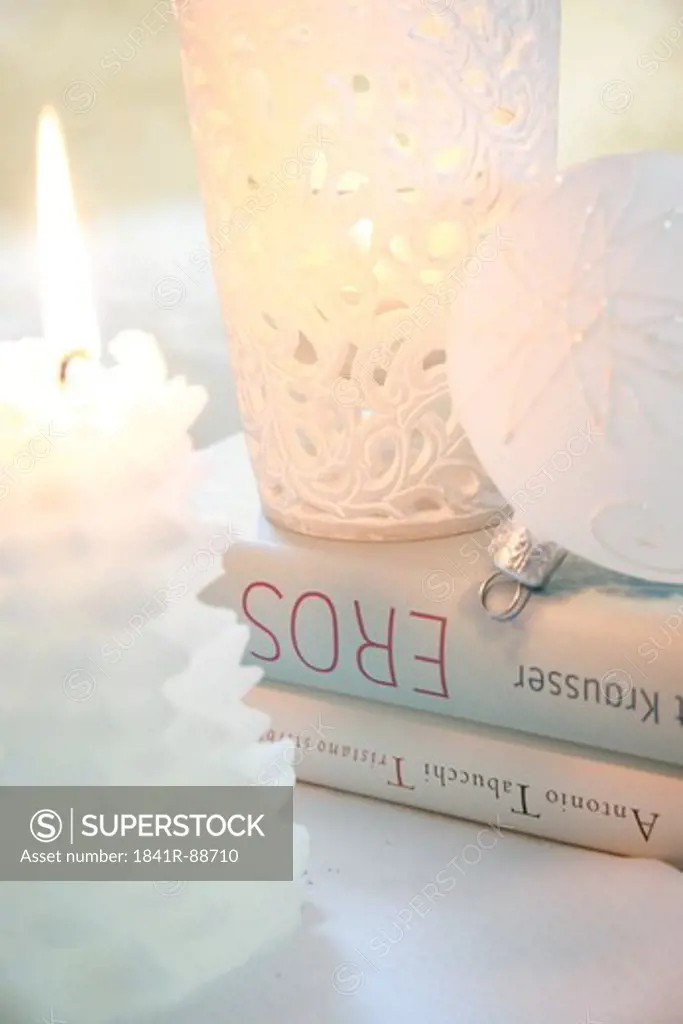 Close-up of Christmas ornament with burning candle and books