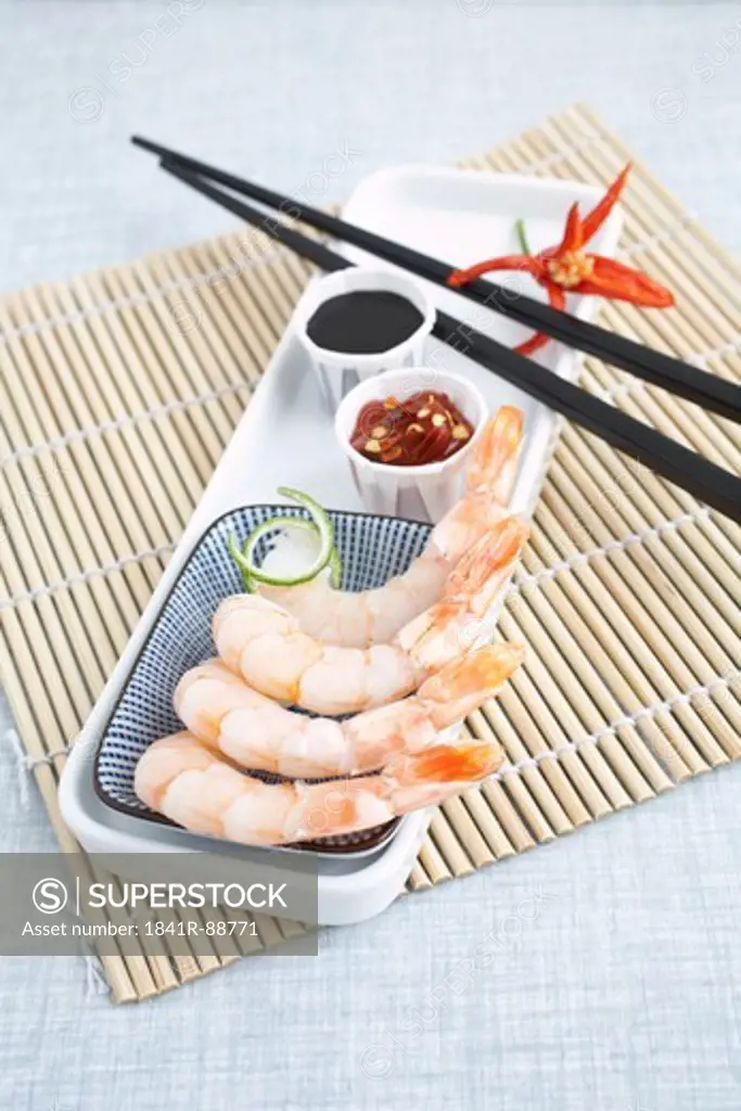 Raw shrimps with chopsticks and sauce on tray