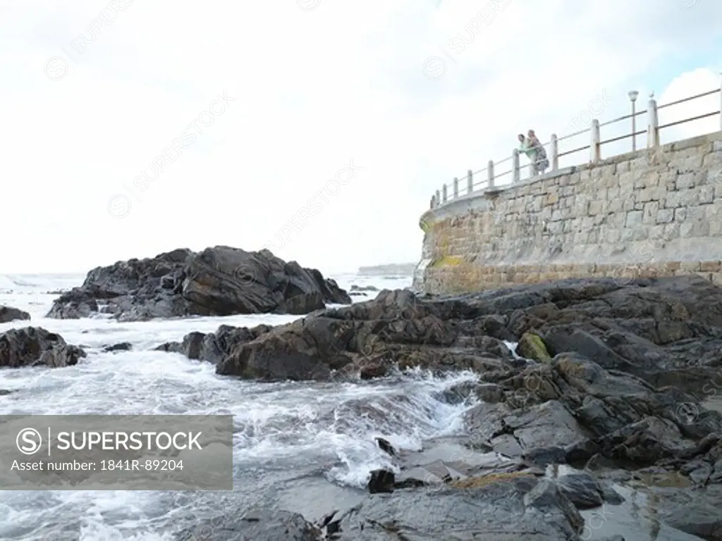 Couple leaning on railing at coast