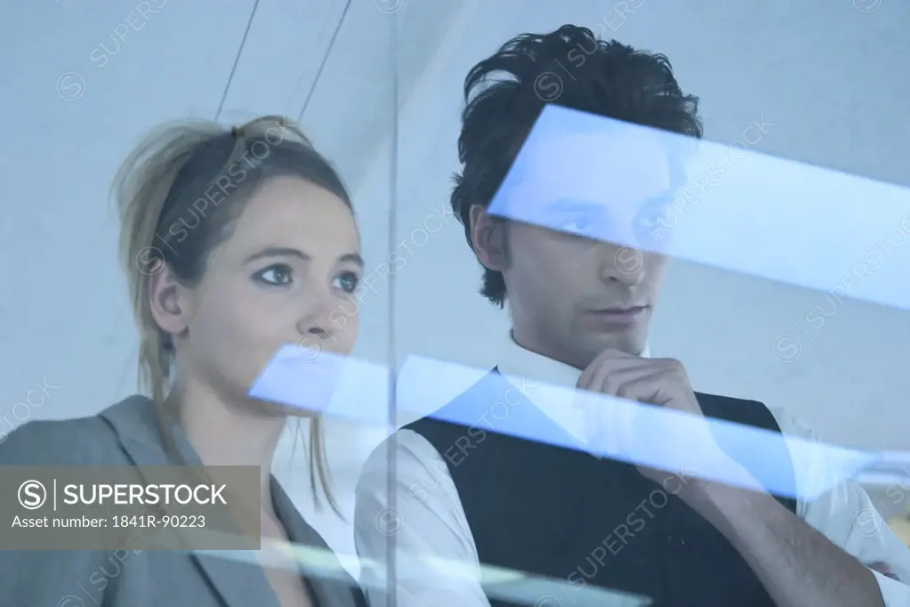 Businessman and businesswoman looking through window