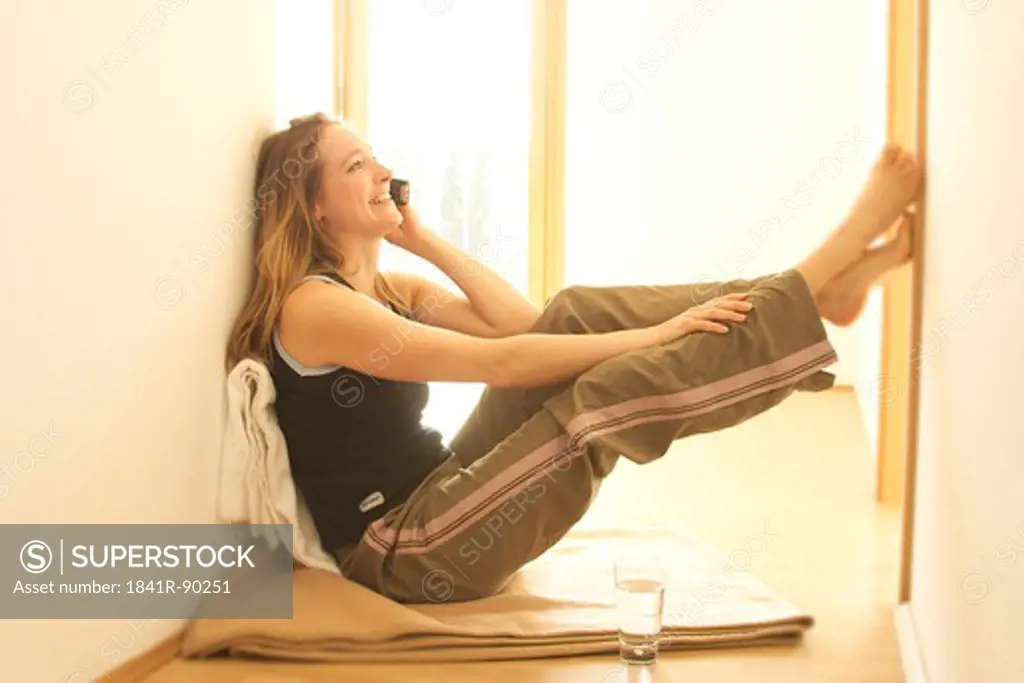 Side profile of young woman talking on mobile phone by window