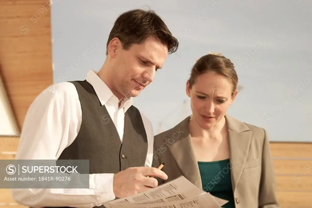 Close-up of two businesspeople looking at documents on terrace