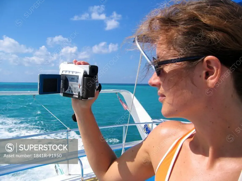 Woman filming sea with home video camera