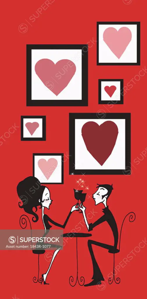 Couple toasting at cafe table in front of framed hearts