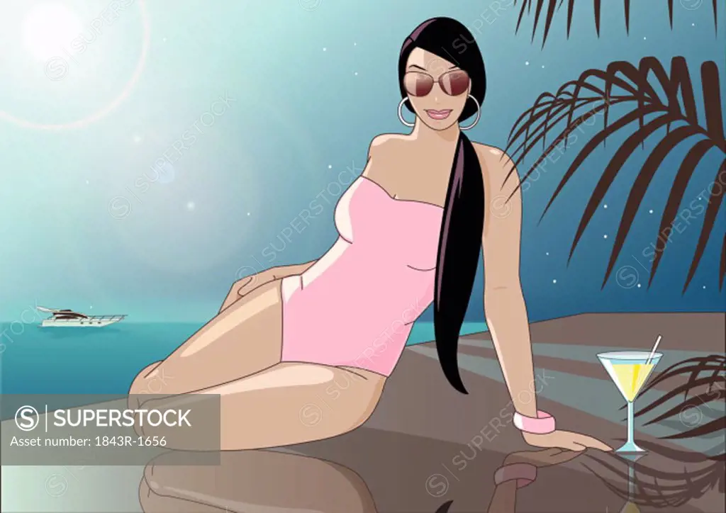 Woman in a pink bathing suit and sunglasses lounging by the water with a cocktail