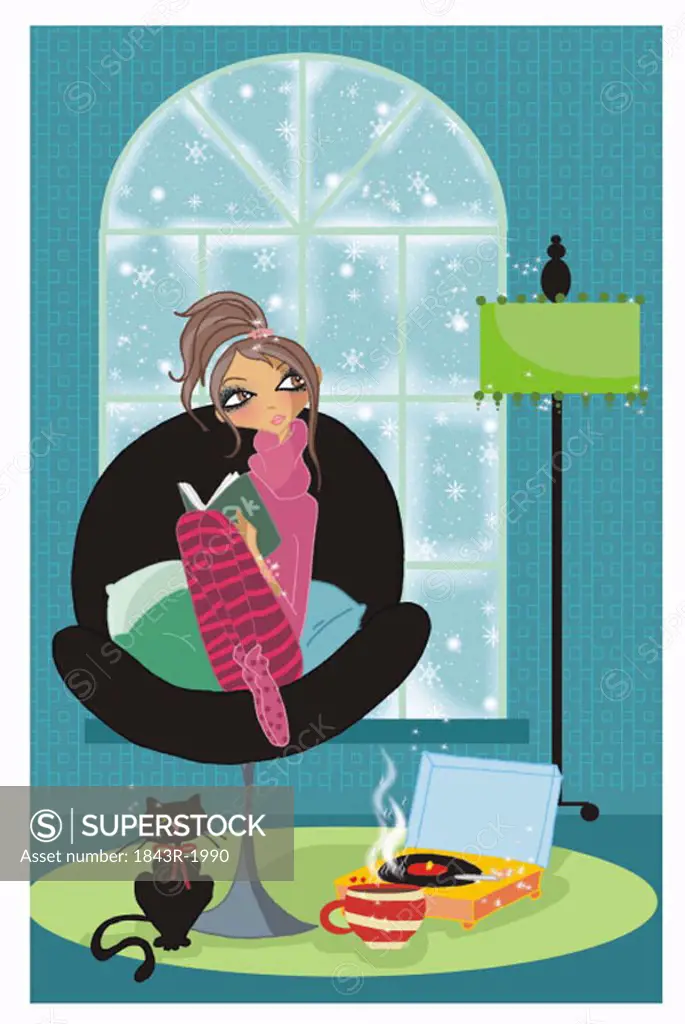 Young woman curling up on chair with a book