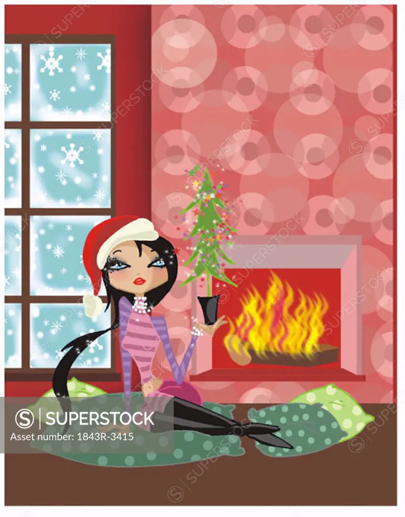 Woman sitting by the fire with a little Christmas tree