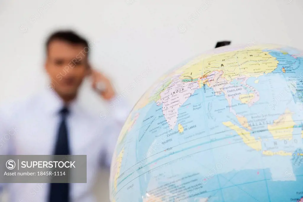 Close-up of a globe with a businessman in the background