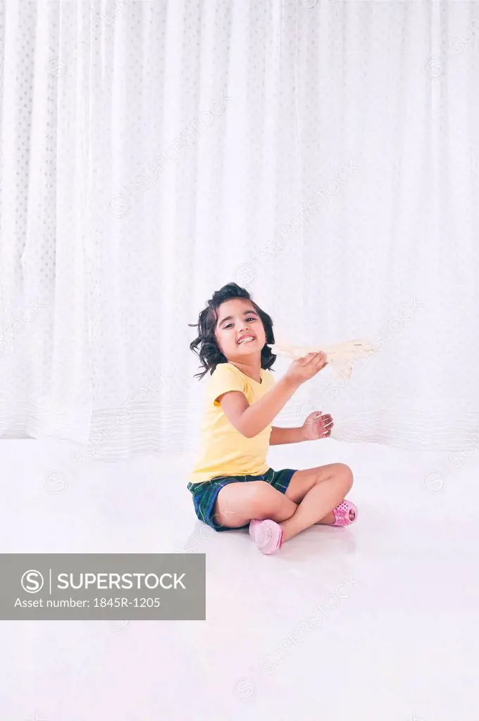 Girl playing with toy aeroplane and smiling