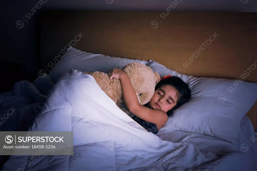Girl sleeping on the bed with a teddy bear