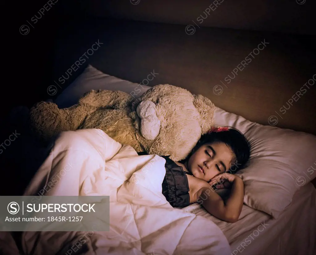 Girl sleeping on the bed with a teddy bear