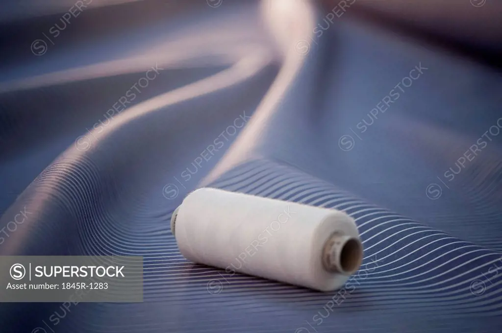 Close-up of a spool of thread on a fabric