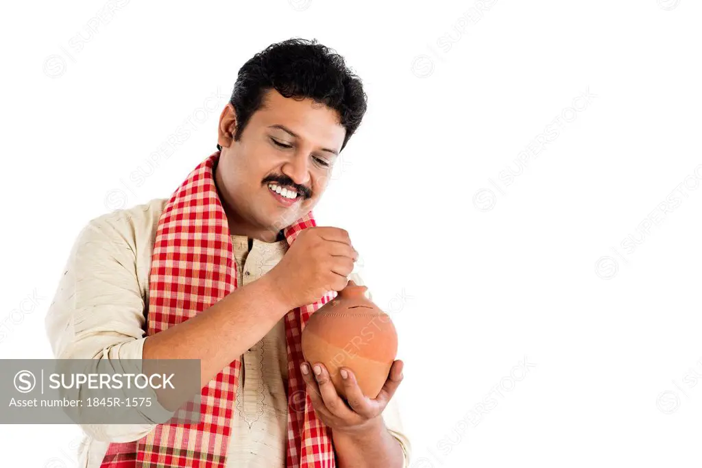Man putting a coin into a piggy bank and smiling
