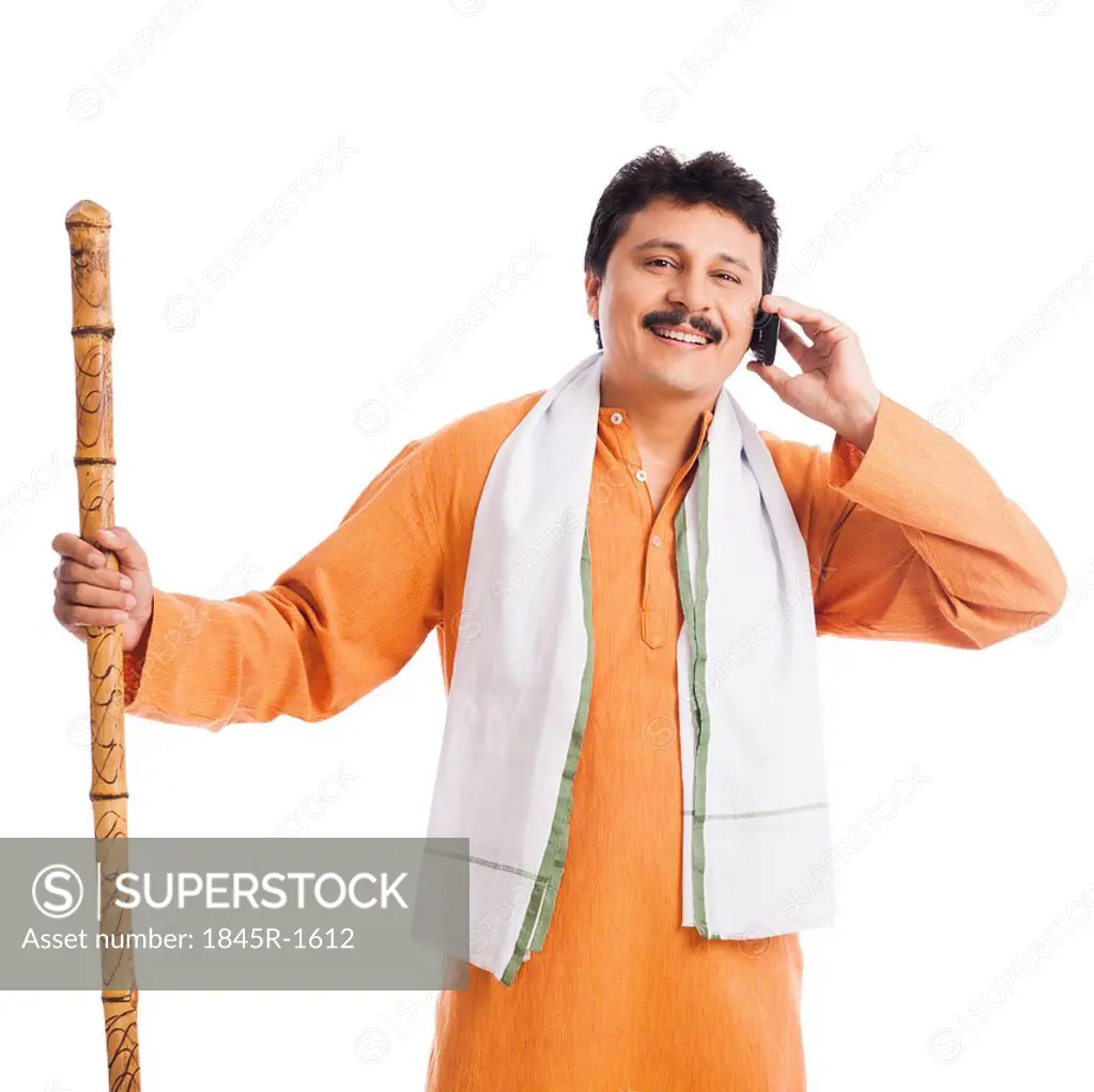Portrait of a man holding a wooden staff and talking on a mobile phone