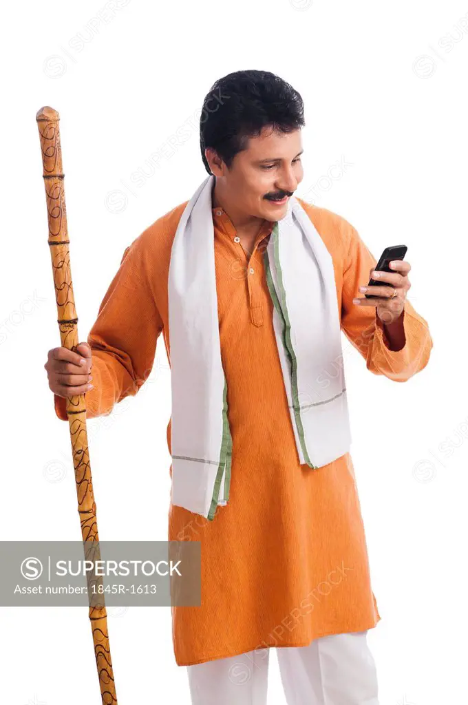Close-up of a man holding a wooden staff and using a mobile phone