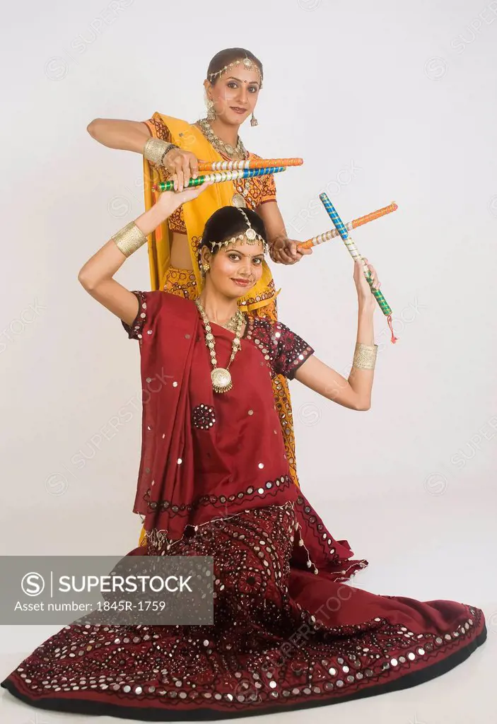 Two women performing dandiya