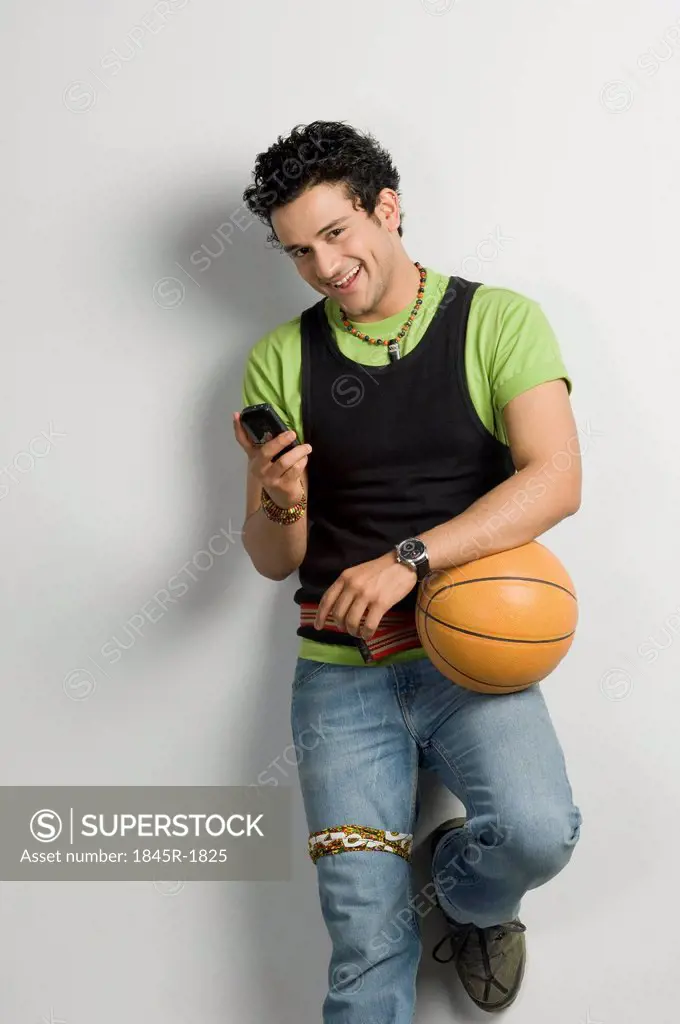 Man holding a basketball and using a mobile phone